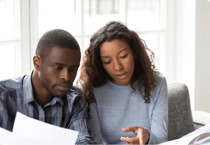Man and woman sitting together reviewing documents in a bright room.