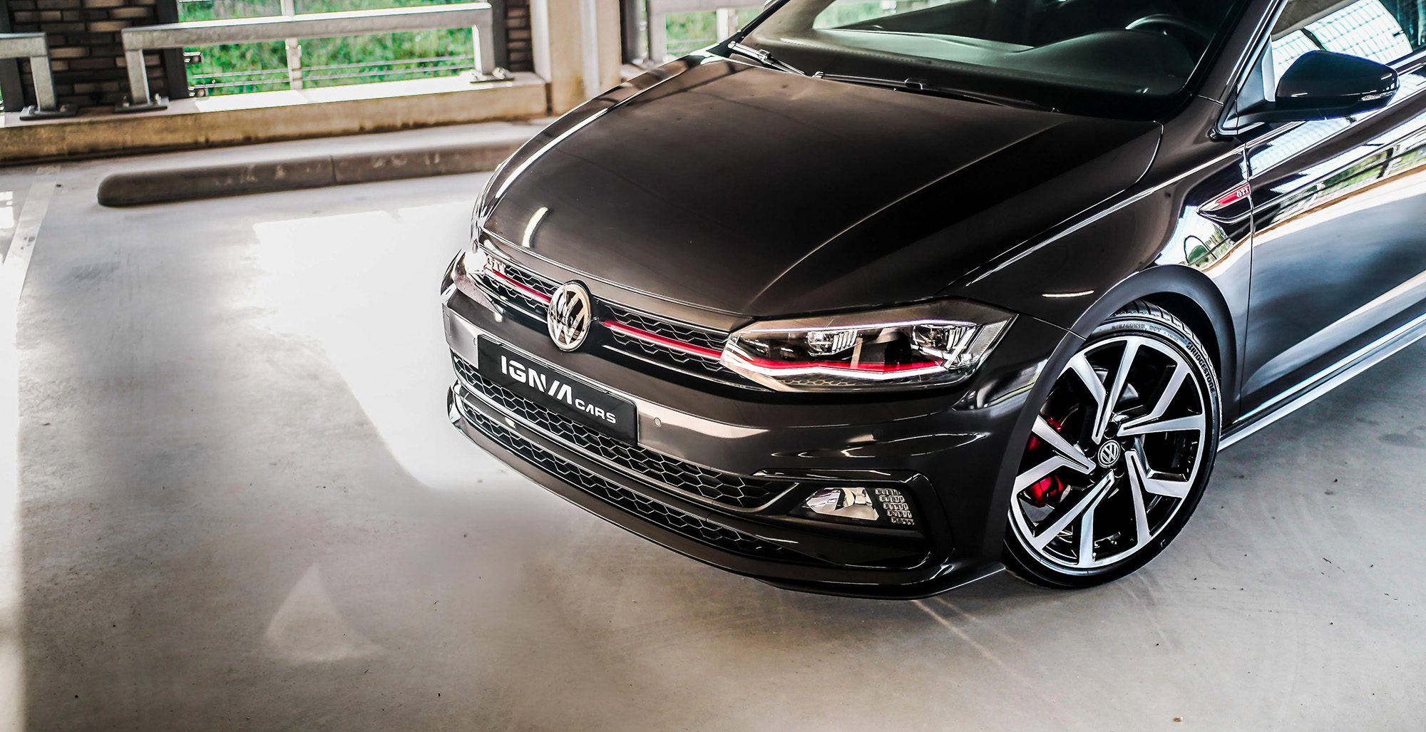 Voorste deel van zwarte Volkswagen auto met glanzende velgen geparkeerd in garage.