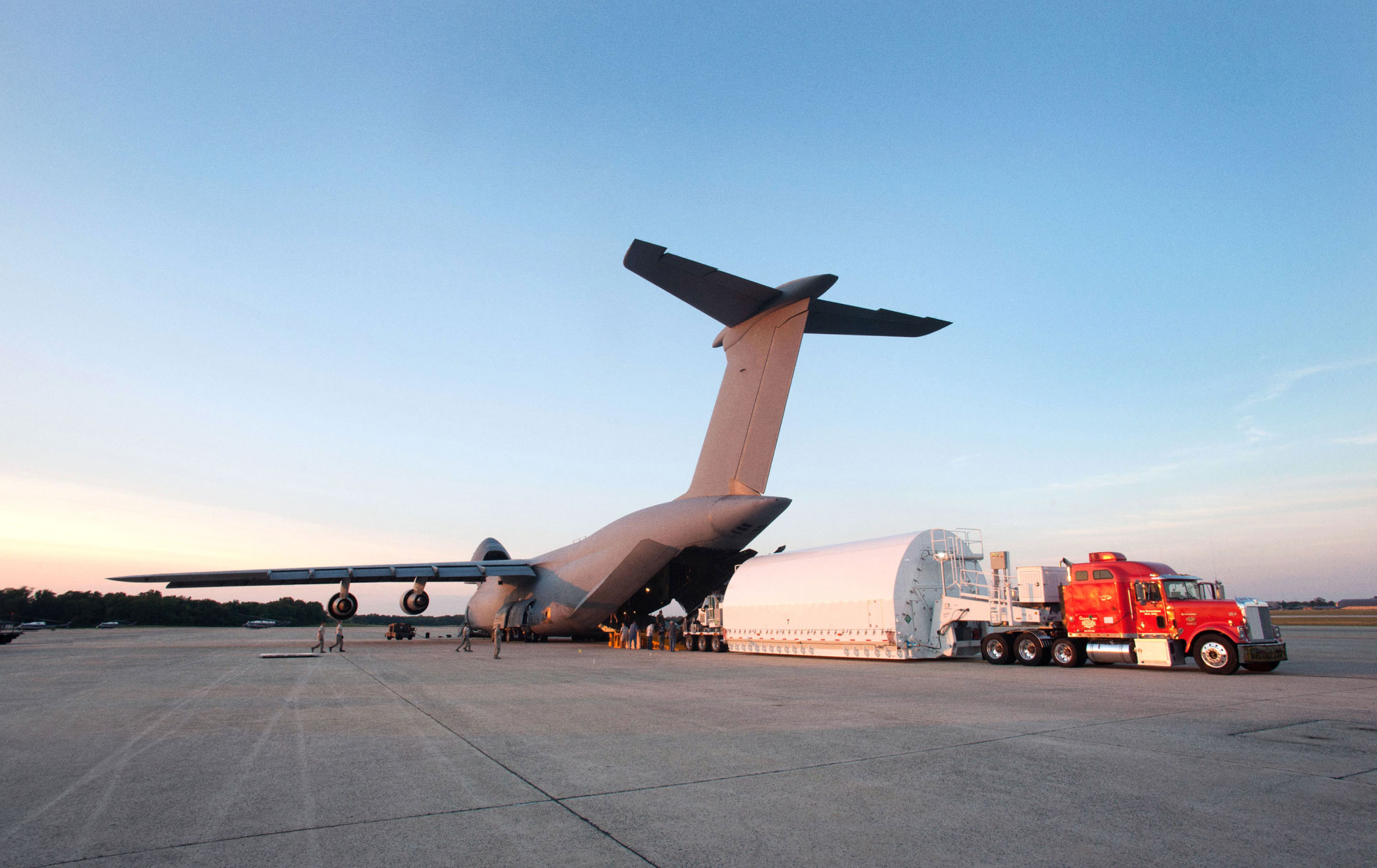 A crew loading Telescope parts from a truck onto a plane