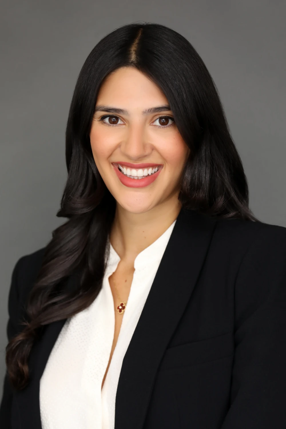 woman with black hair in coat smiling