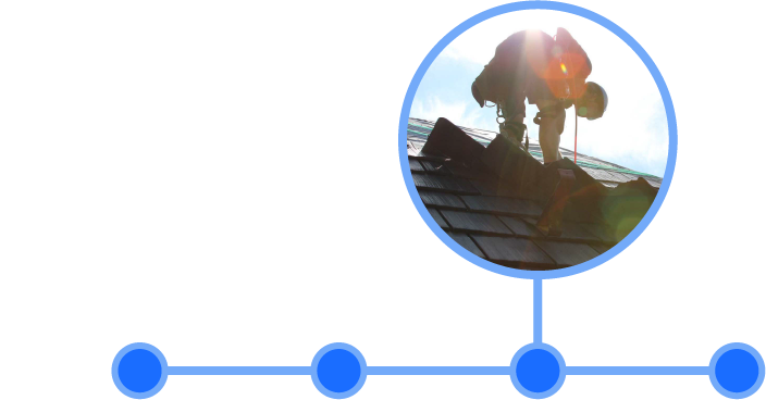 Worker wearing a safety harness installing shingles on a roof in bright sunlight.