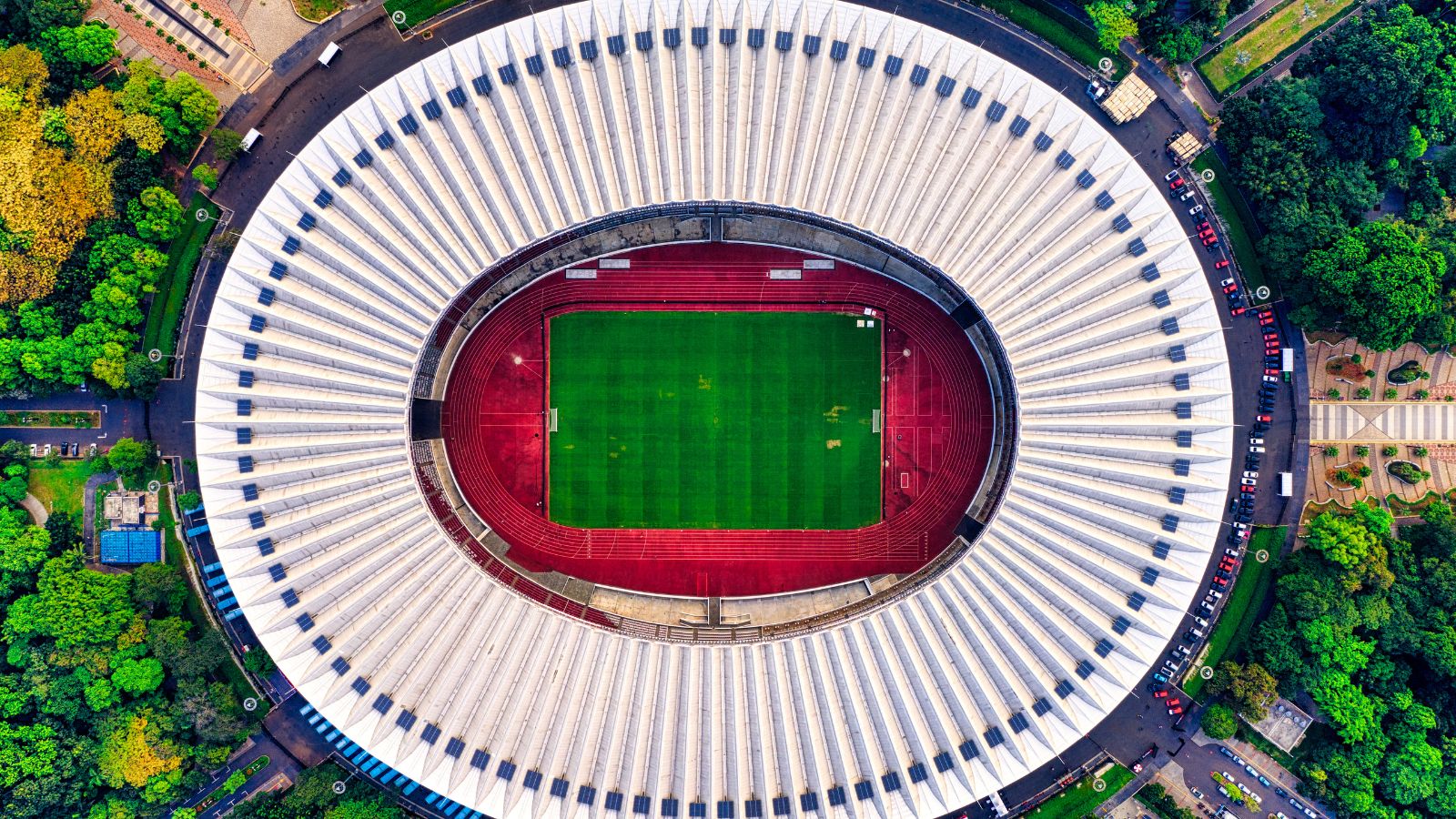 Aerial view of a large football stadium with an oval running track and green pitch at the center, captured from above to represent matchday analysis and professional football coverage.