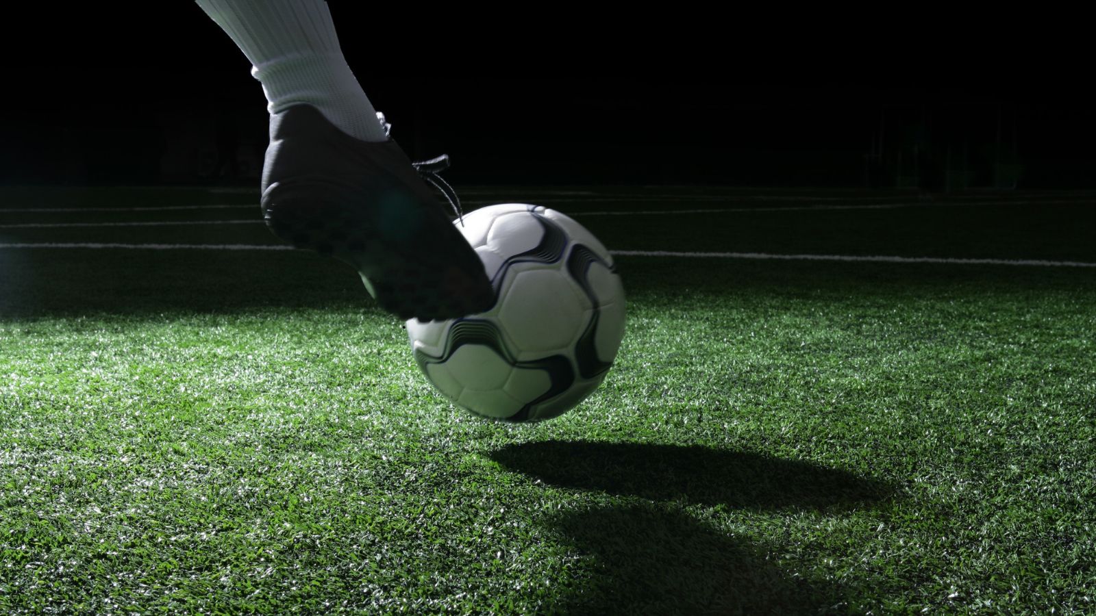 Football boot striking the ball on a dark pitch symbolizing goal-focused football analysis and daily premium goal picks.