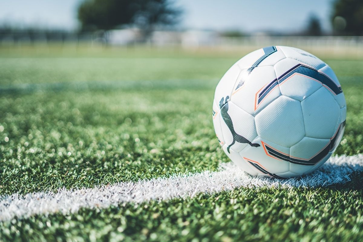 Football resting on the touchline of a green grass pitch before kickoff, symbolising match analysis and goal-focused previews for today’s games.