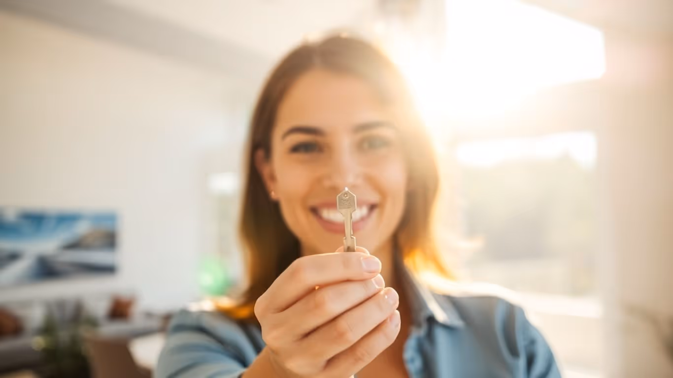 Person holding house key, symbolizing mortgage refinance success.