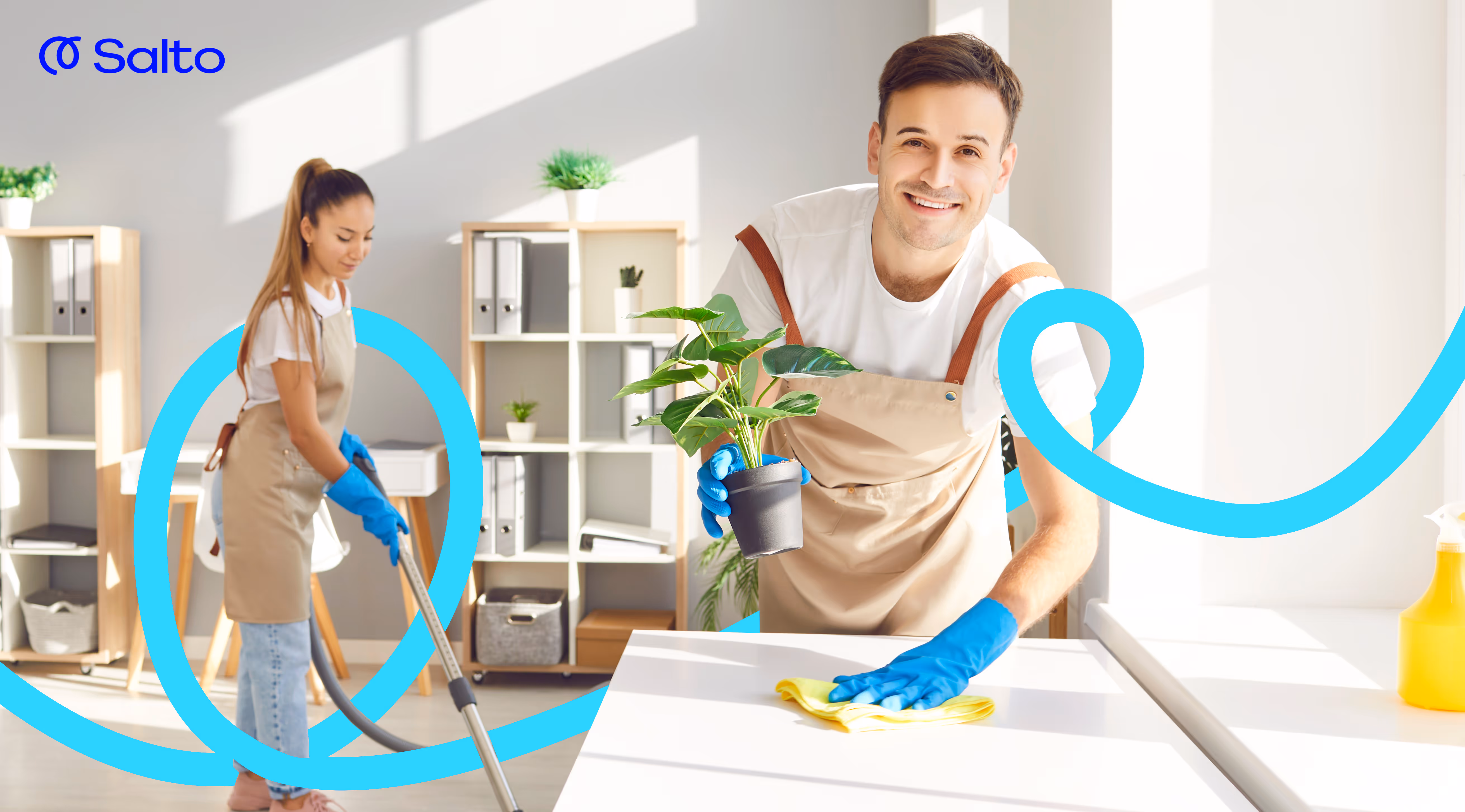 To renholdere som rengjør et lyst kontor; en mann tørker en overflate mens en kvinne støvsuger i bakgrunnen.