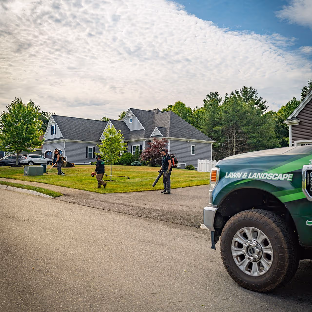Lawn maintenance crew mowing and trimming a residential property by OFlaherty Lawn Care in Attleboro Massachusetts near me
