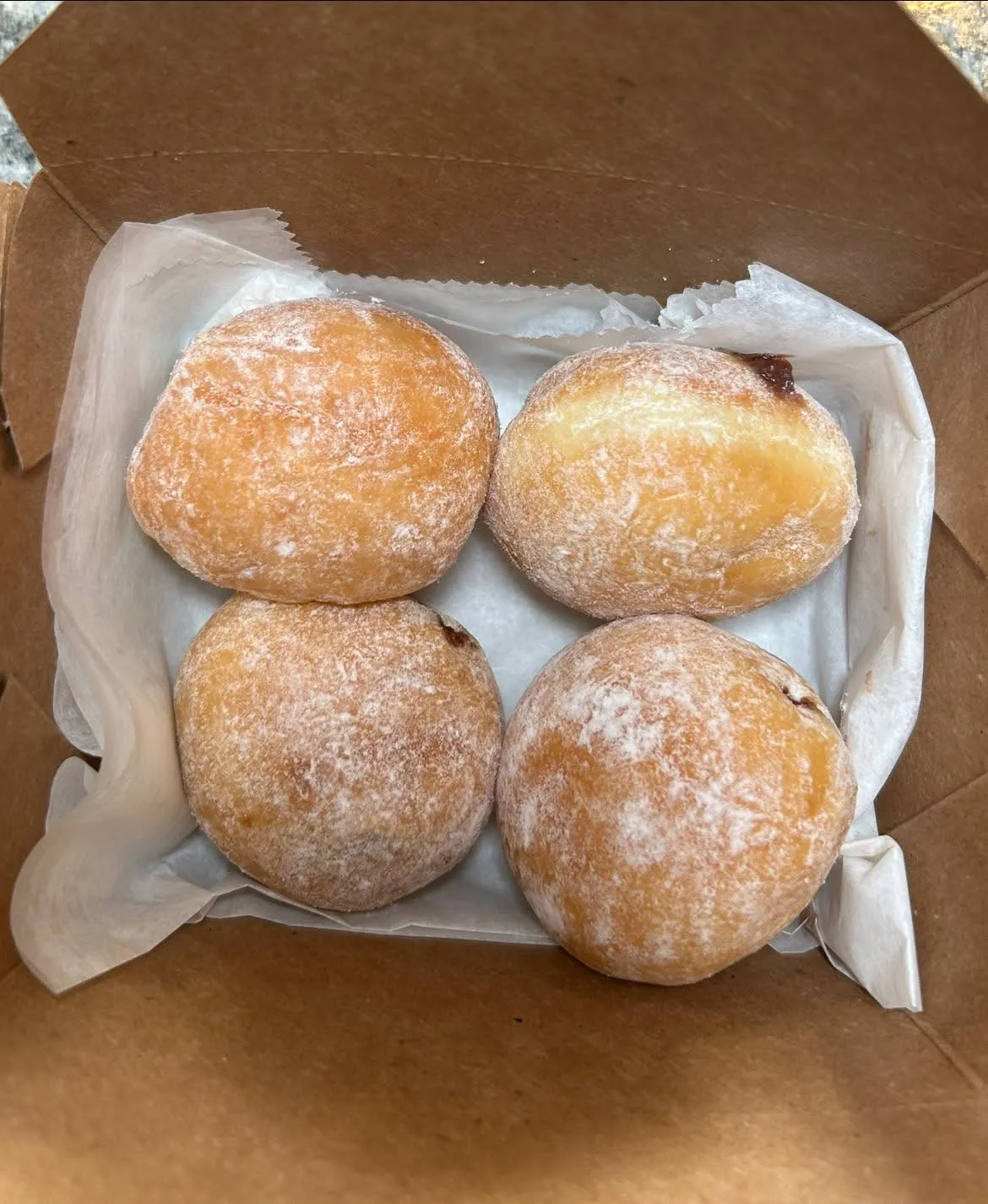A box of doughnuts with a white paper bag.