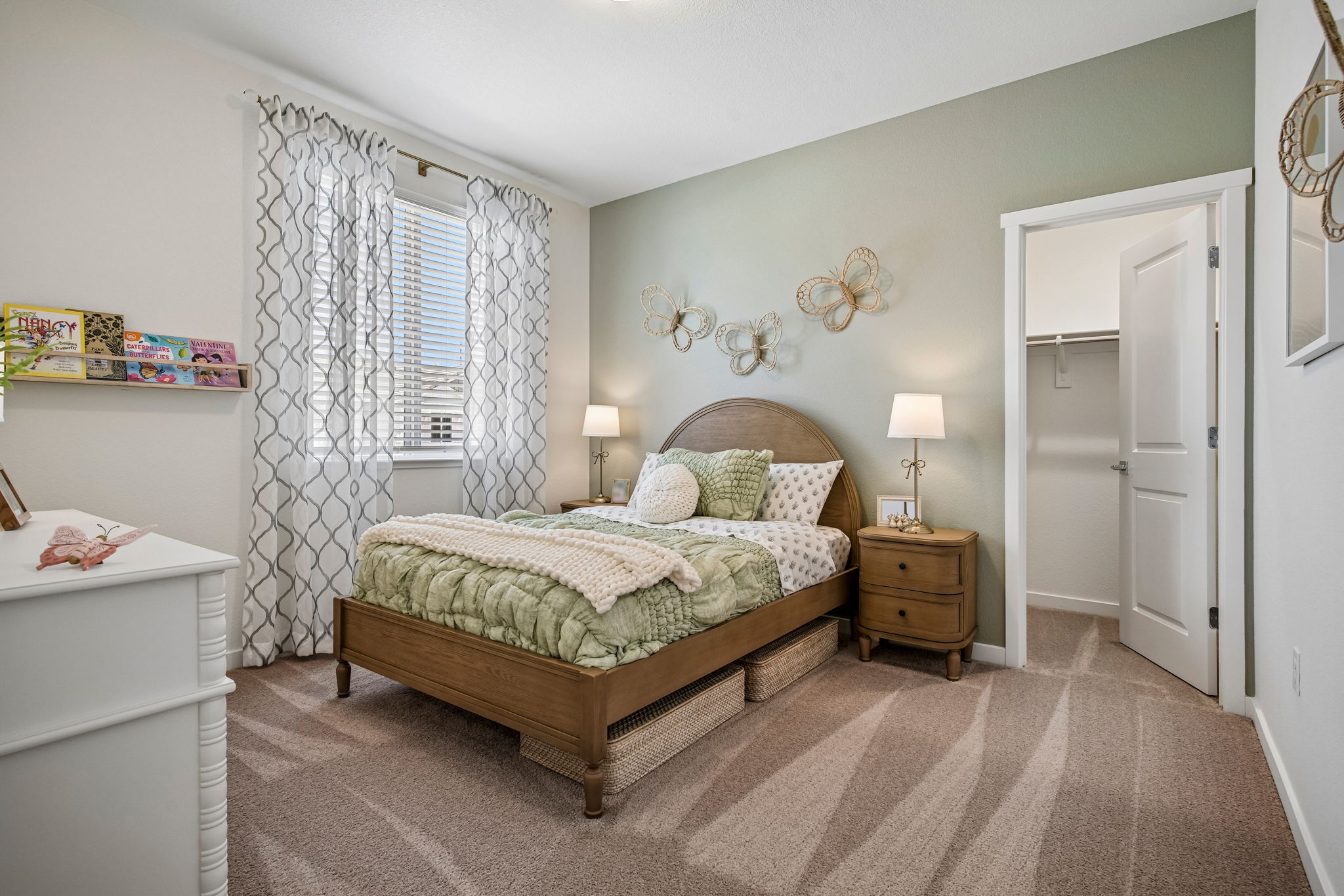 Bedroom with bed, large window, table with lamp, and walk in closet