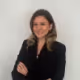 Portrait of a smiling woman with shoulder-length hair wearing a black blazer with her arms crossed.