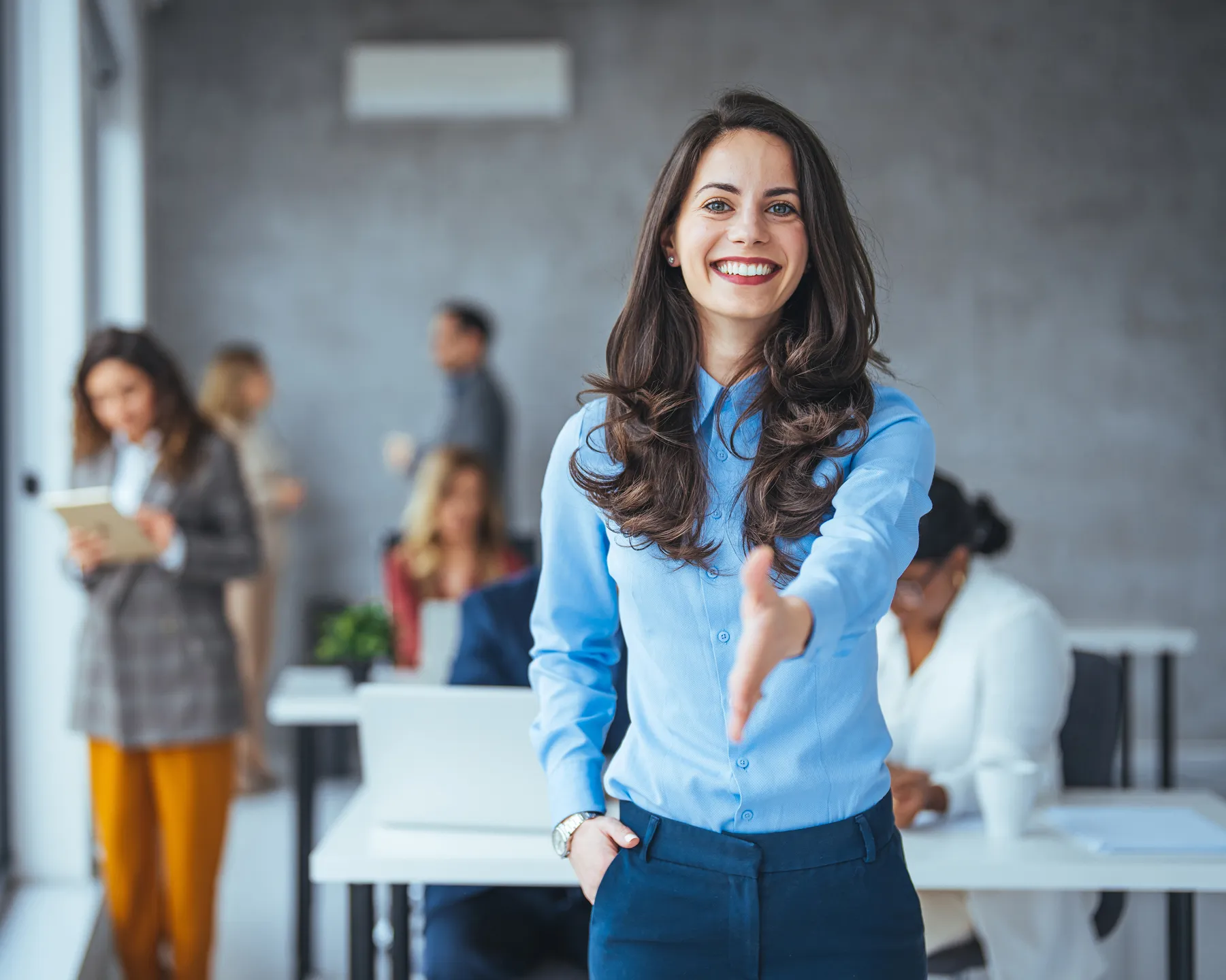 Two professional women smiling and discussing something on a laptop in a modern office.