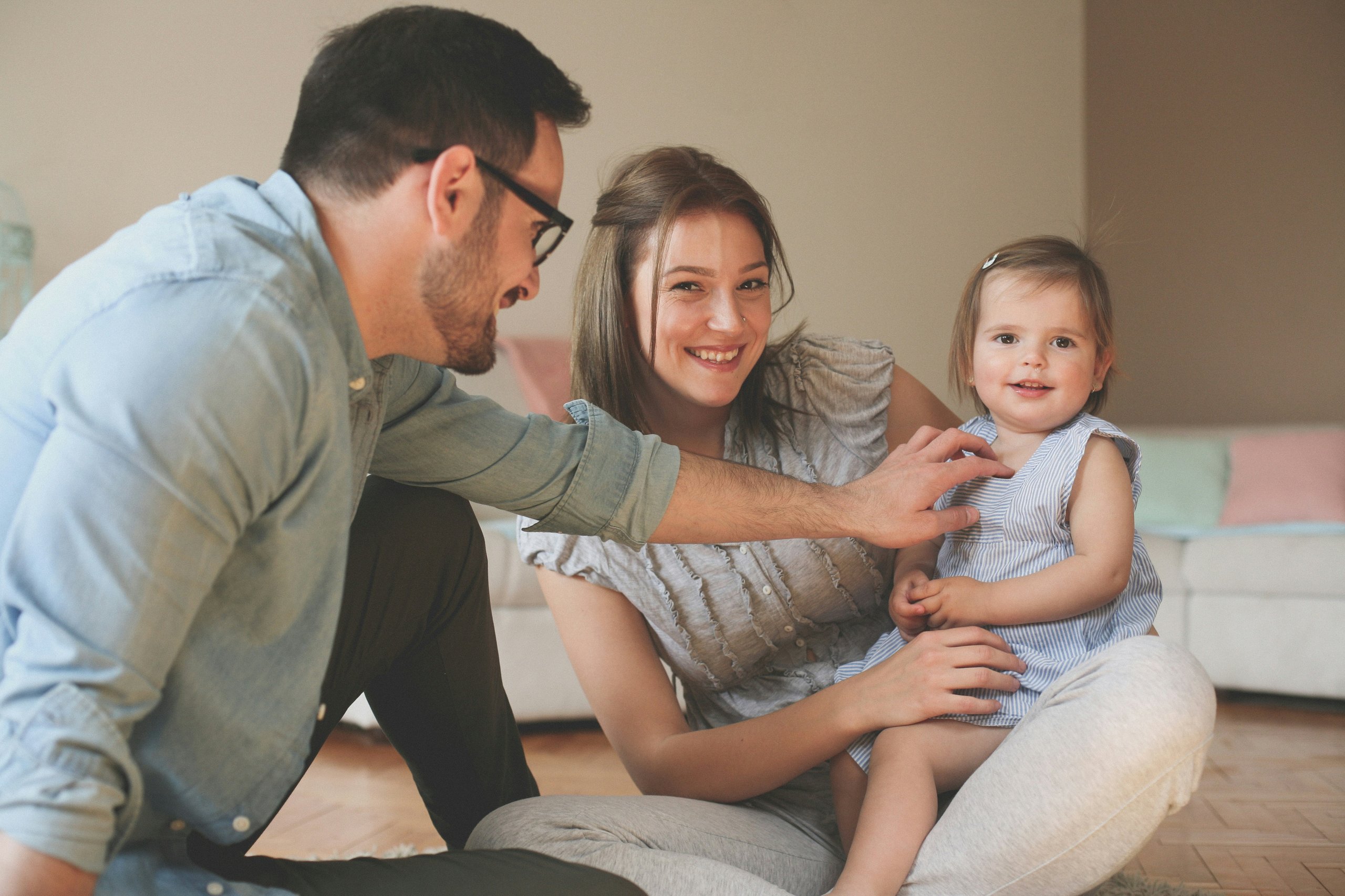 Happy family playing together on floor, parents smiling with young child