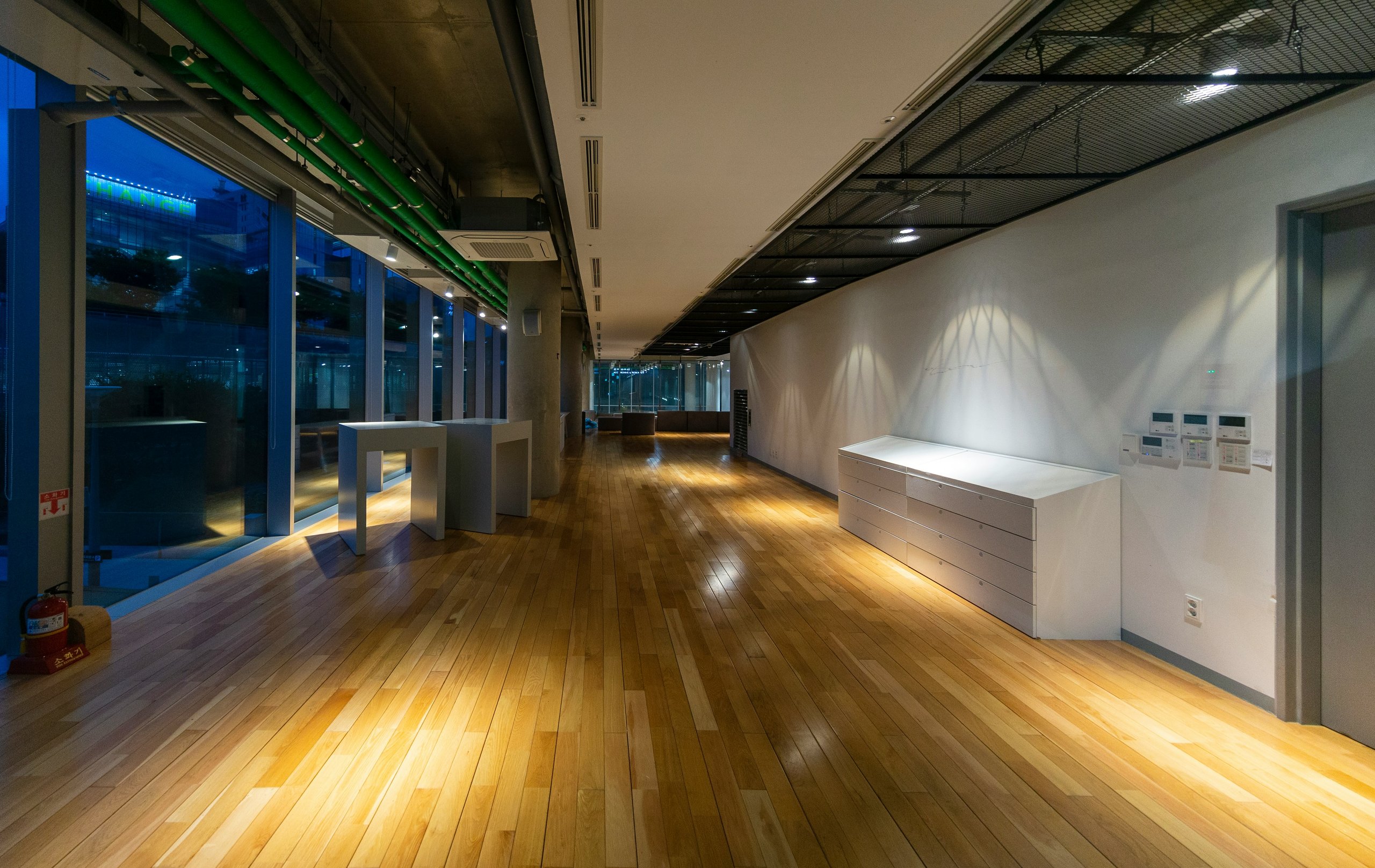 Empty modern office interior with wooden floor and glass windows at night
