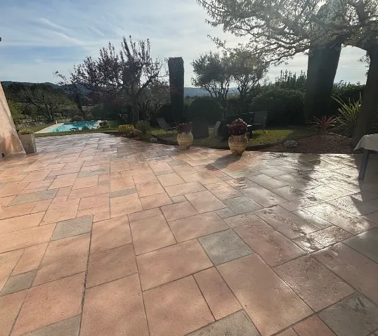 Piscine rectangulaire avec marches immergées, bordée d'une terrasse en bois et d'un espace repas avec chaises et table.