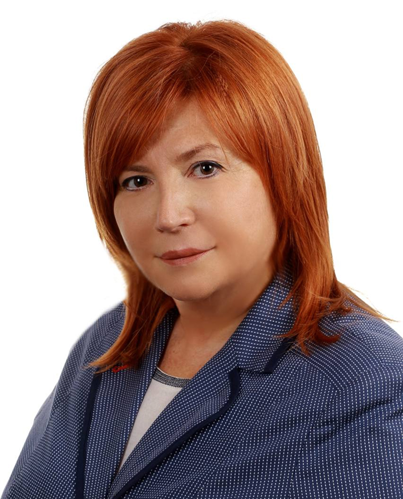 Жінка з рудим волоссям у сірому светрі з коміром-гольф на світлому фоні.