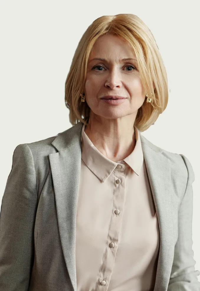 Professional middle-aged woman with blonde hair wearing a light grey blazer and beige button-up shirt.