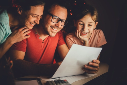 A happy family of three smiling while looking at a document together, representing family bonding or positive planning.