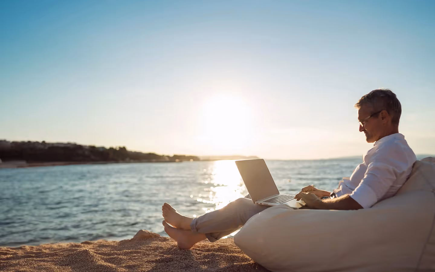 man on beach using a laptop