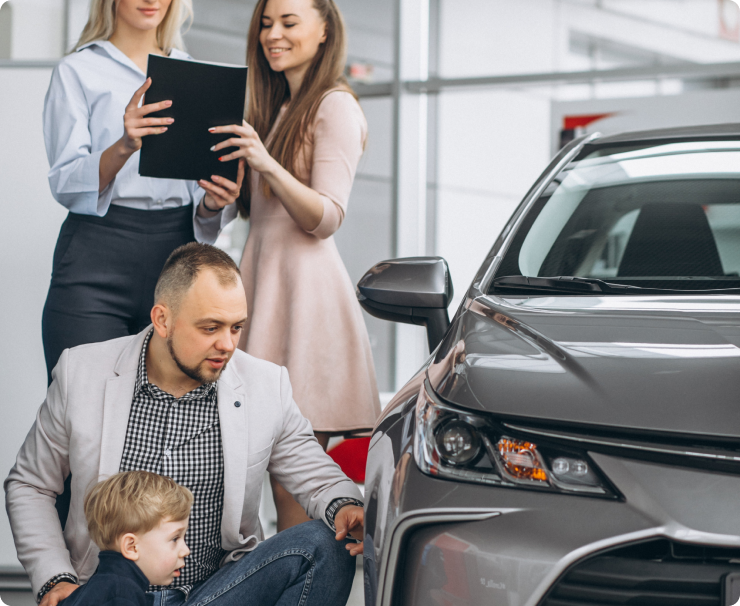 Family with two children reviewing a vehicle with a dealership sales consultant inside a showroom.