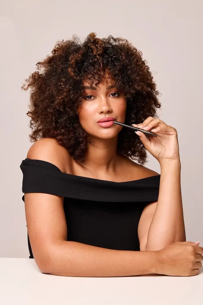 Black metal rolling cart with two shelves and a light-colored top on a concrete floor against a gray concrete wall and white platform.