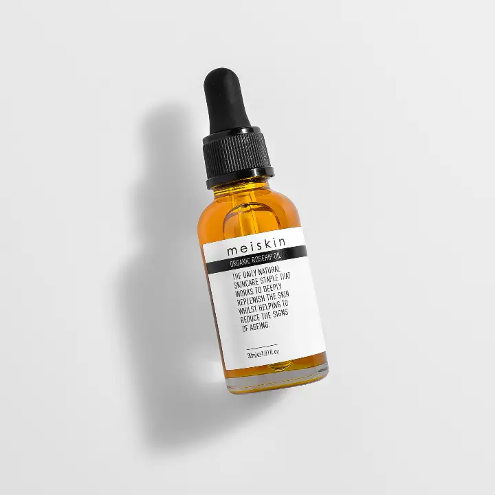 Black metal rolling cart with two shelves and a light-colored top on a concrete floor against a gray concrete wall and white platform.