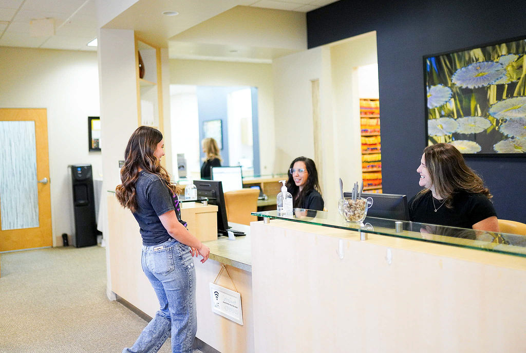 A patient checking in at the front desk with two team members at Ogden Orthodontics