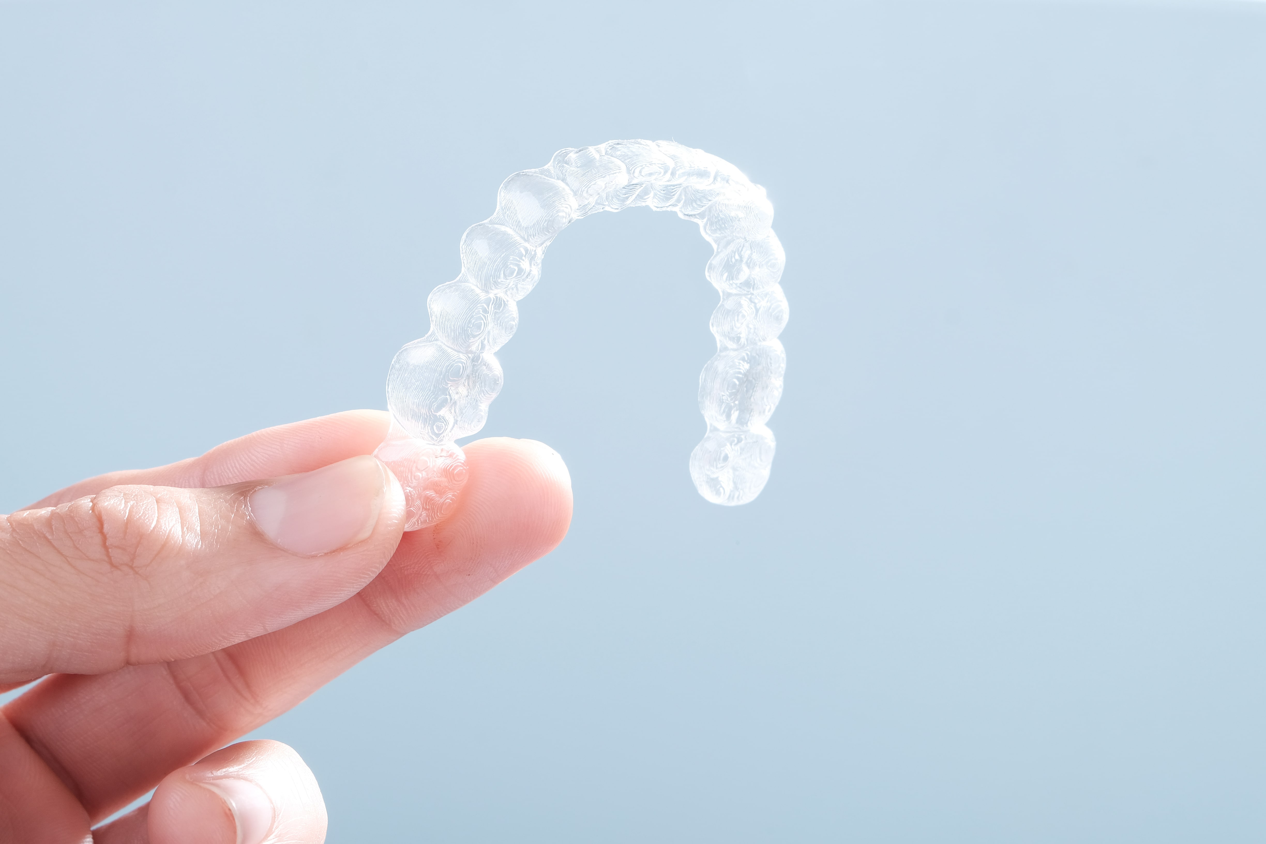 Patient holding a clear Invisalign aligner tray at Ogden Orthodontics