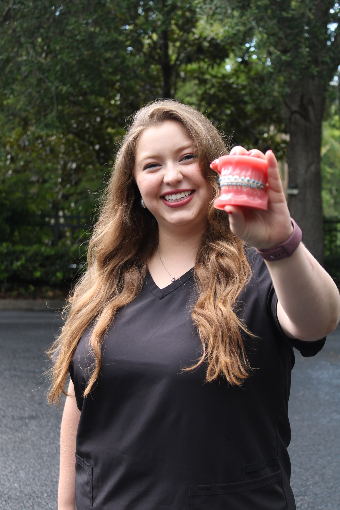 Smiling Ogden Orthodontics team member holding a model of teeth with braces