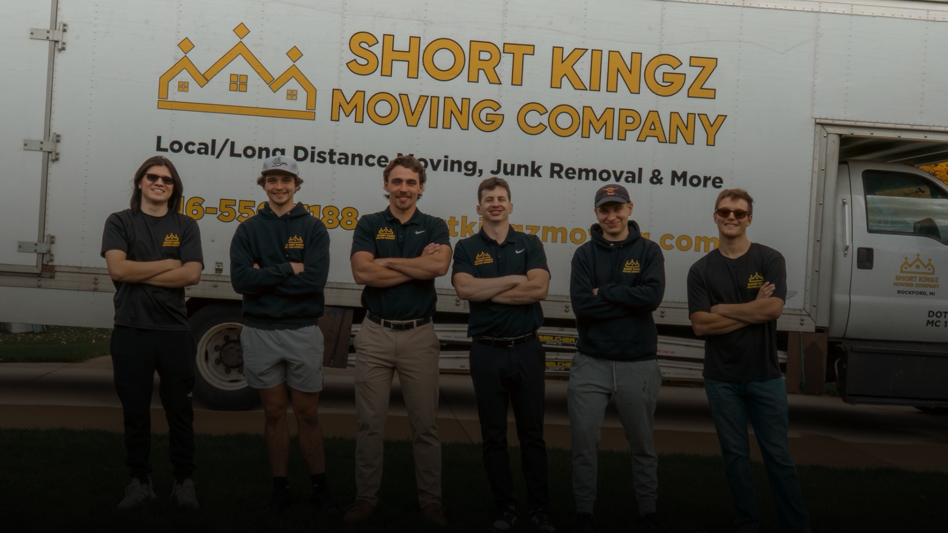 Six men standing with arms crossed in front of a Short Kingz Moving Company truck.
