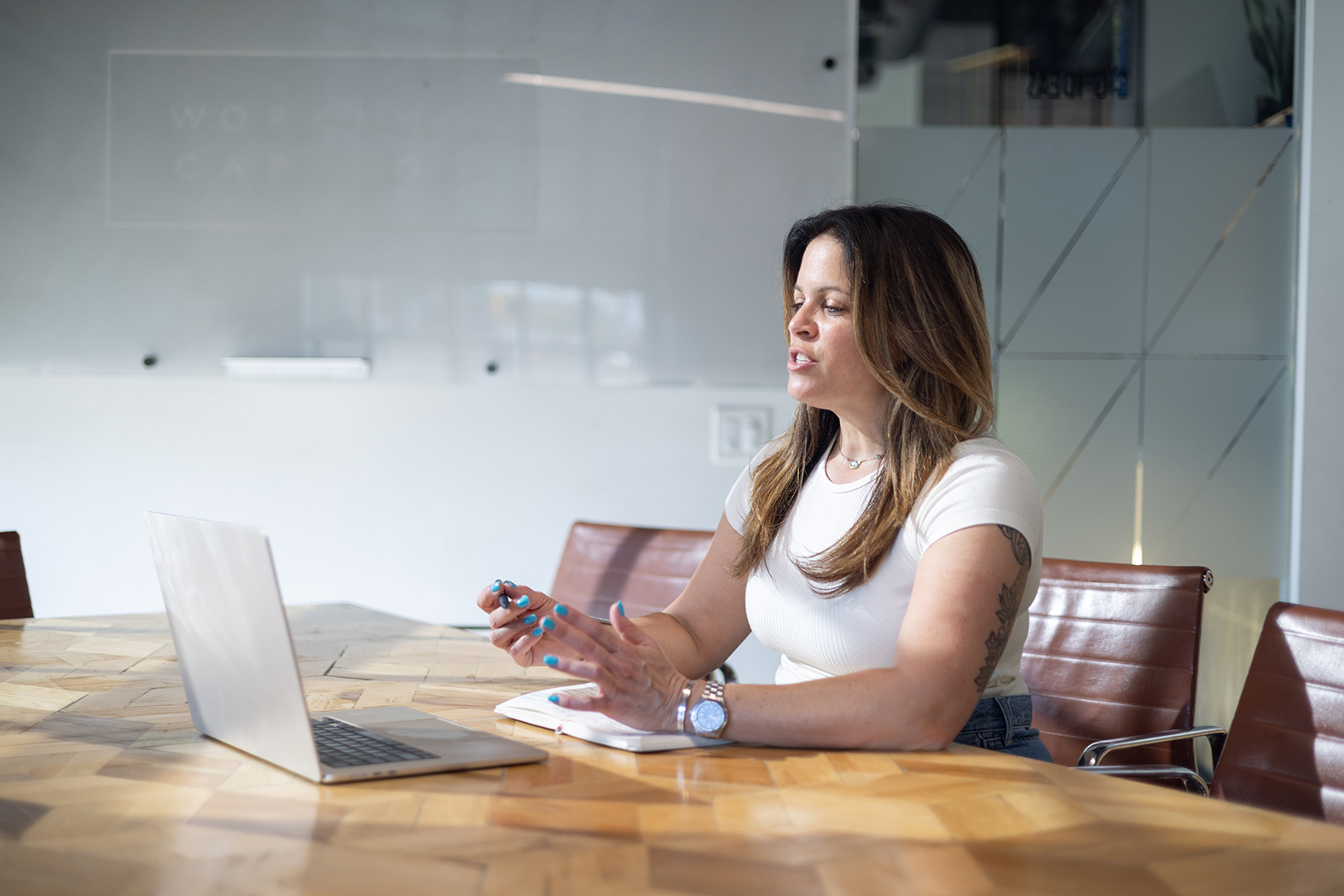 Melissa Silverstein seated at a table using a laptop in a professional workspace
