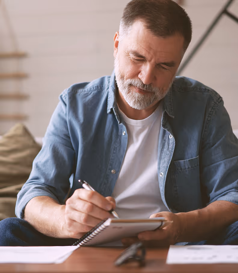 Man seated at a desk writing notes in a professional workspace