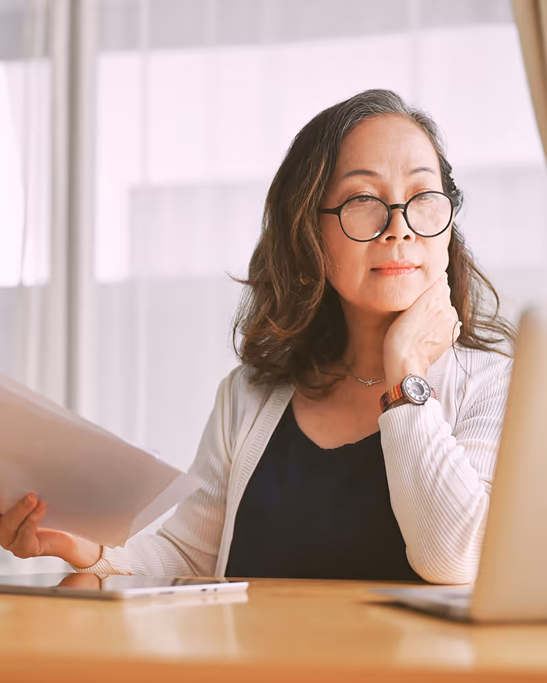Woman seated at a table using a laptop in a professional setting