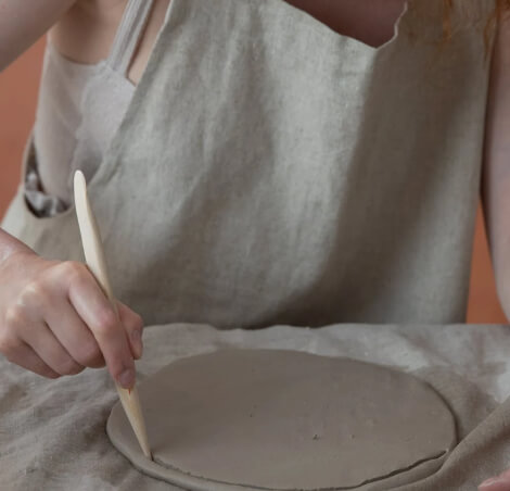 Close-up of a girl cutting wet clay to make a ceramic plate