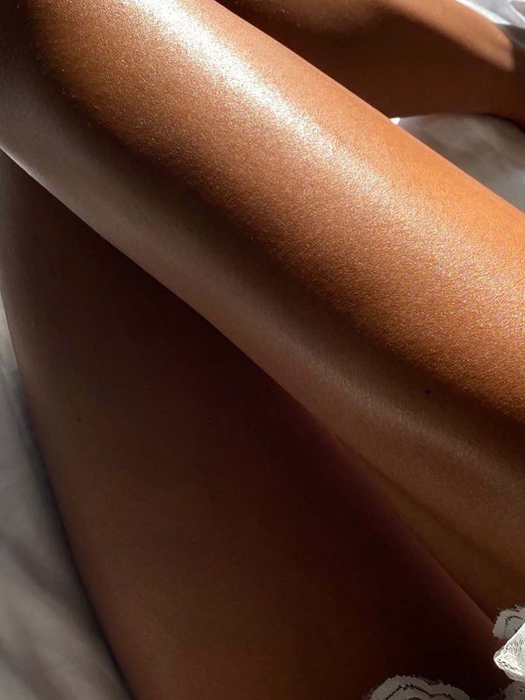 Close-up of smooth, tanned legs with sunlight highlighting the skin's natural glow posing for TANNED TO - an automated spray tan studio in Toronto.