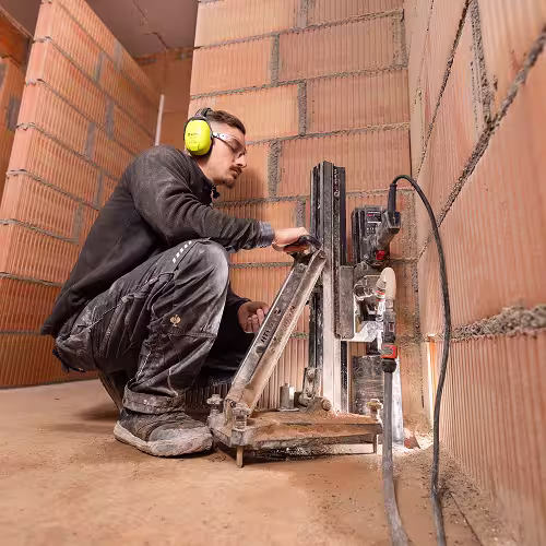 Mitarbeiter von LIPAK Kernbohrungen setzt mit einem Kernbohrgerät eine Bohrung in eine Betondecke