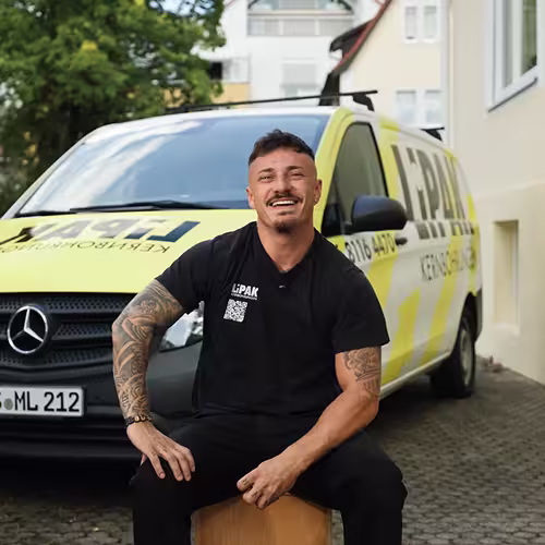 Inhaber von LIPAK Kernbohrungen sitzt im Interview vor seinem Firmenfahrzeug und lacht