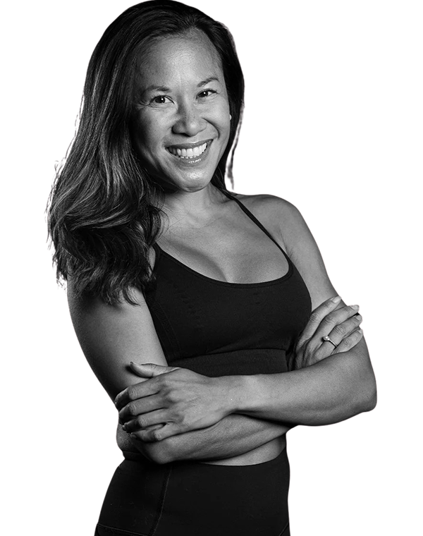 Smiling woman with long hair wearing a black tank top, arms crossed confidently.