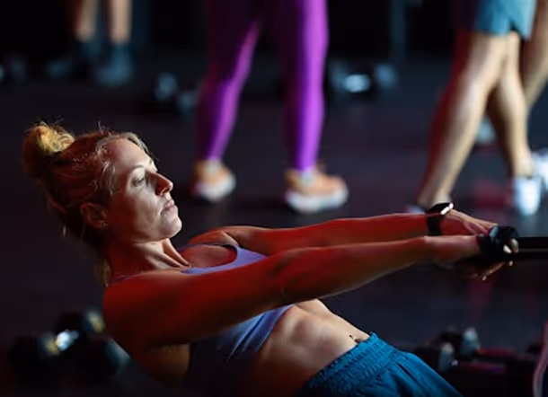 Woman in workout clothes using resistance bands during an exercise in a gym.