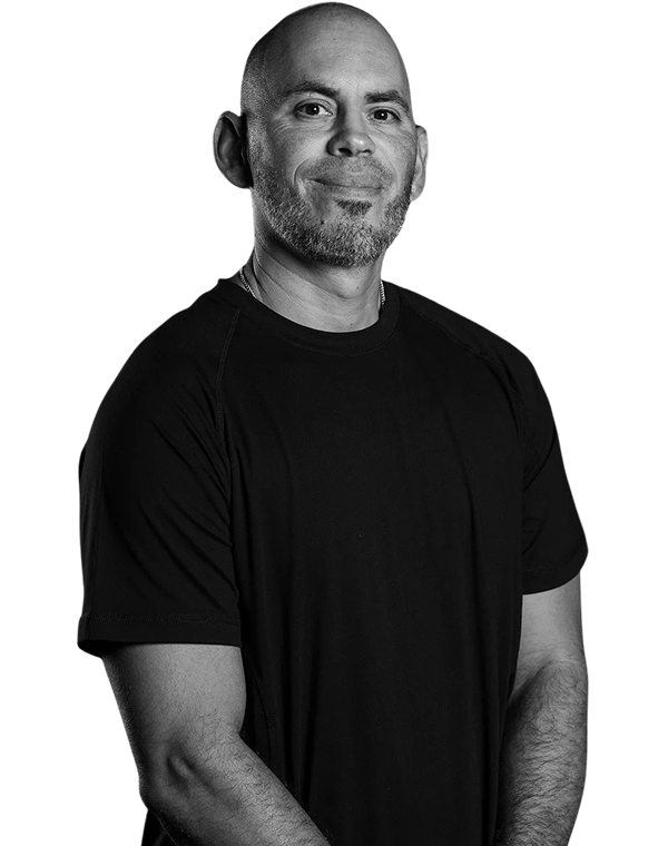 Smiling bald man with a beard wearing a black t-shirt, standing with arms relaxed.