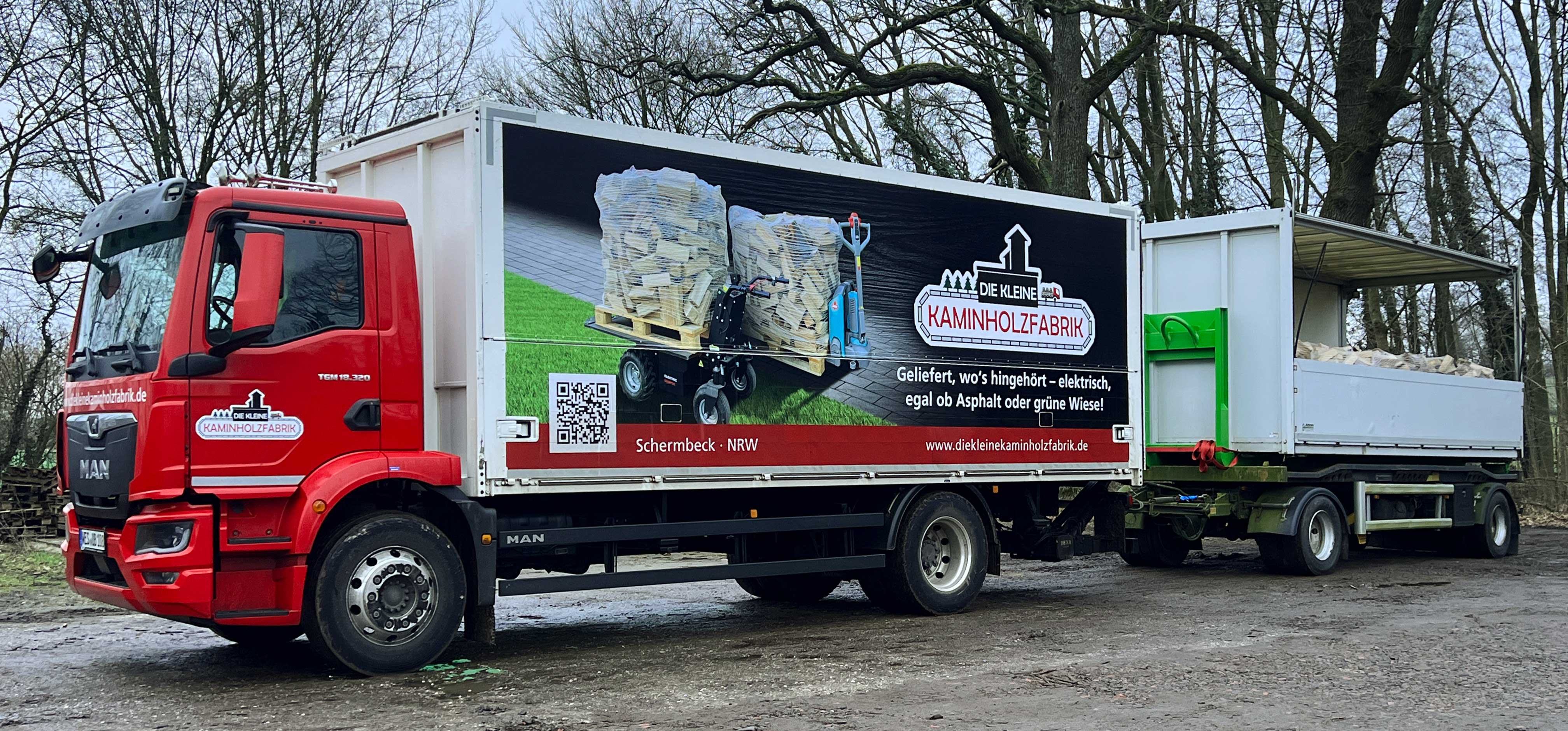 Roter LKW mit Werbung der kleinen Kaminholzfabrik, beladen mit Holz und elektrischer Transportpalette.