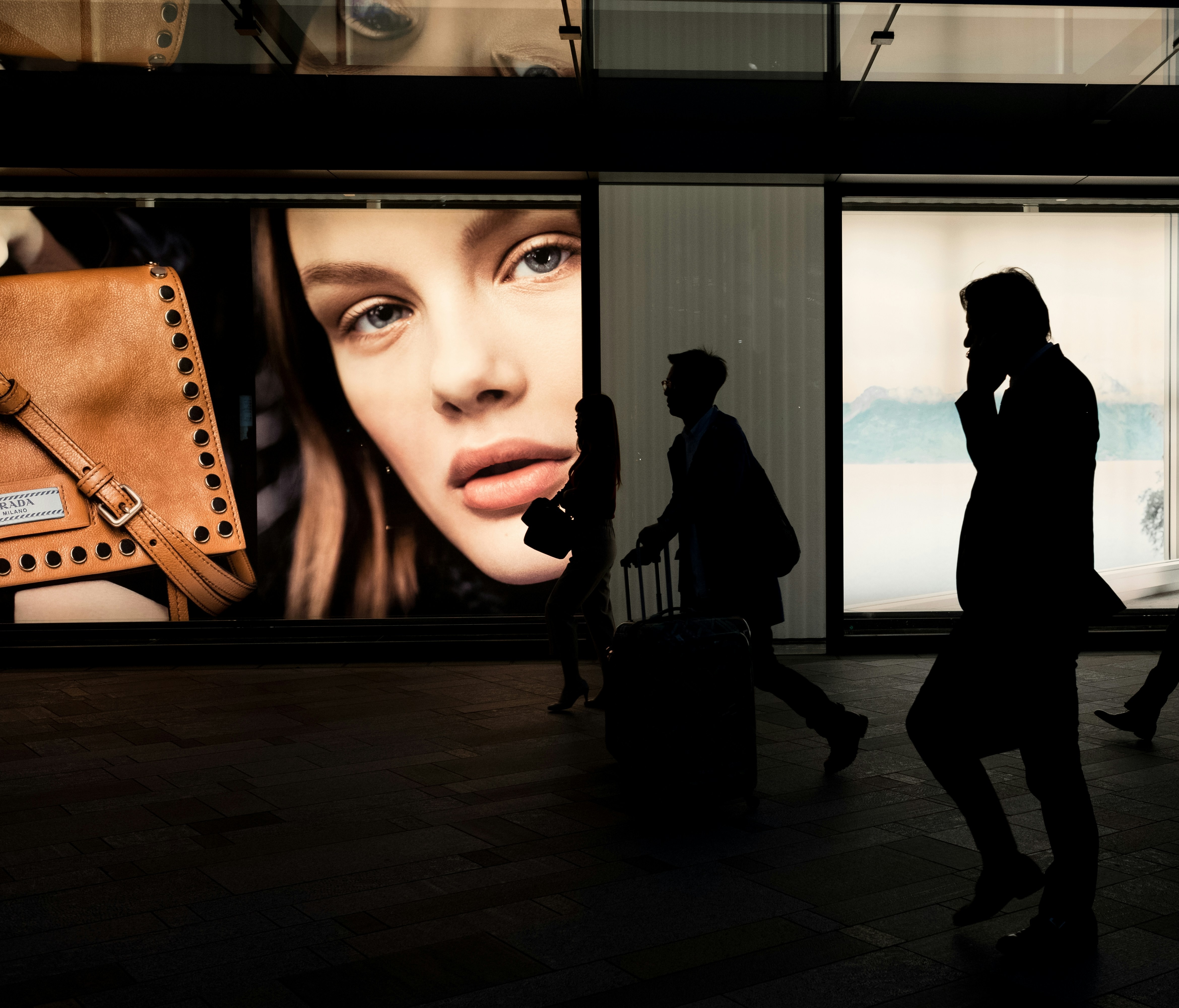 Illuminated fashion billboards with figures walking past