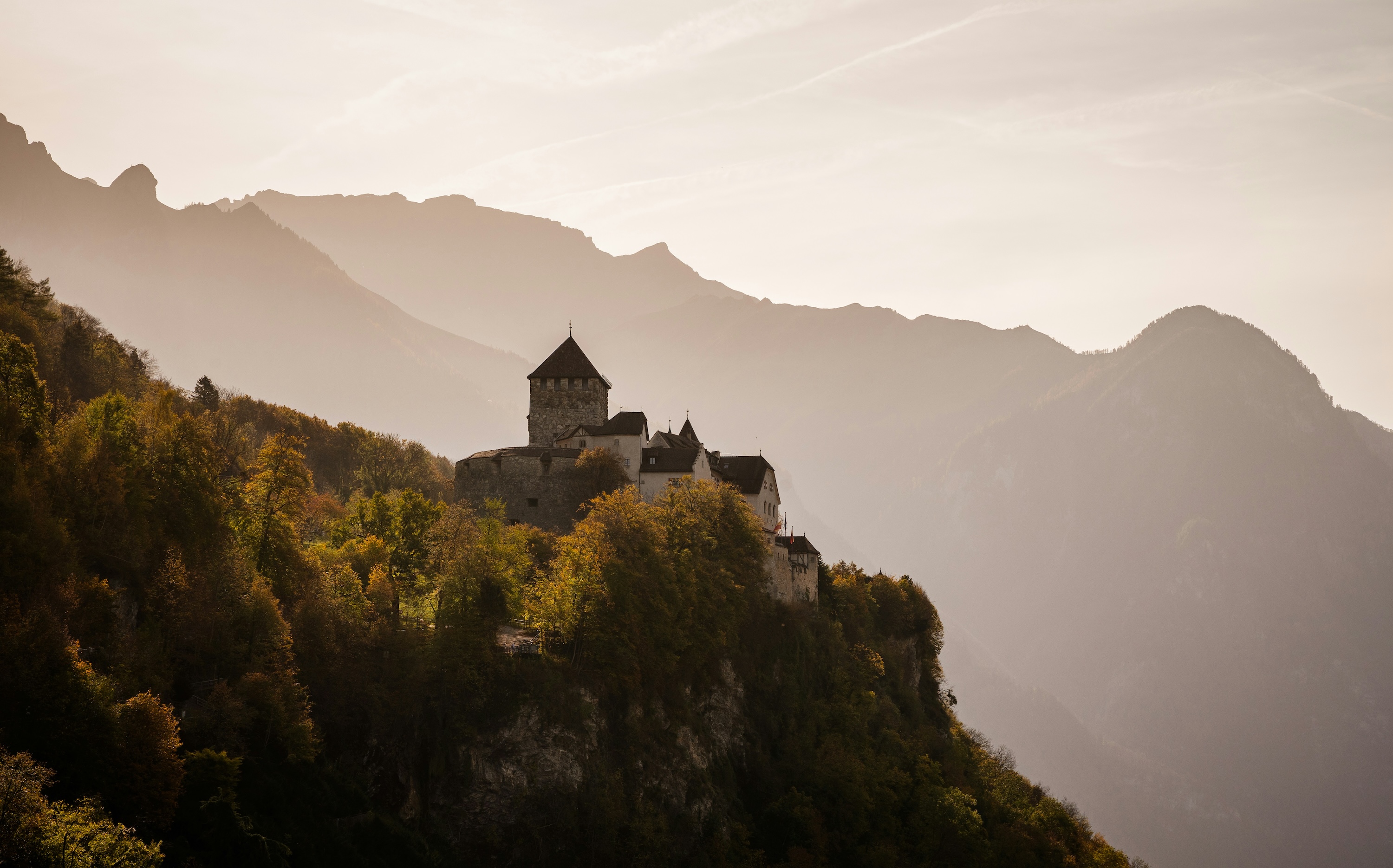 A medieval building in Europe nestled on the side of undulating mountainous terrain