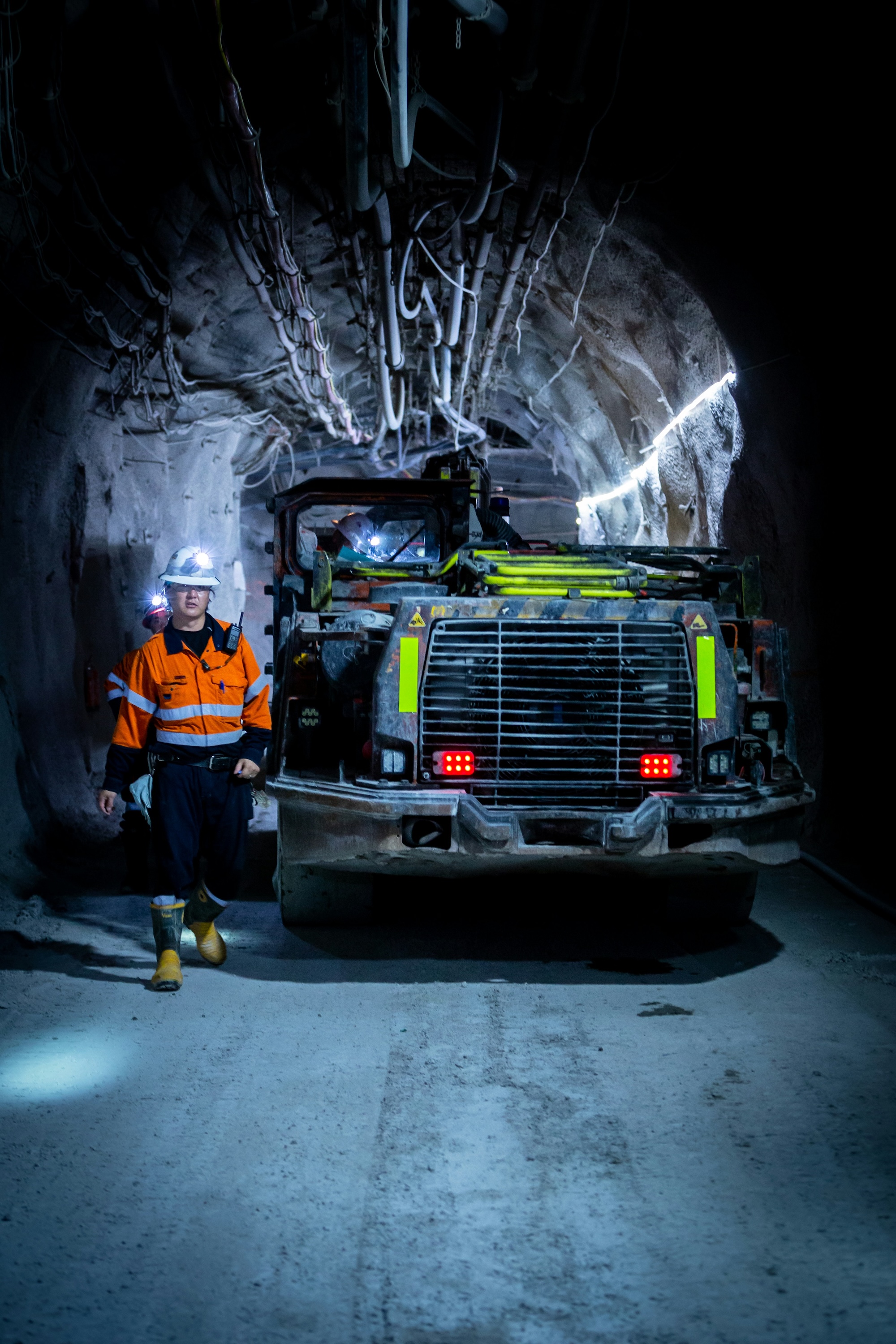 A femail worked in hi-viz clothing beside a vehicle in an underground mine