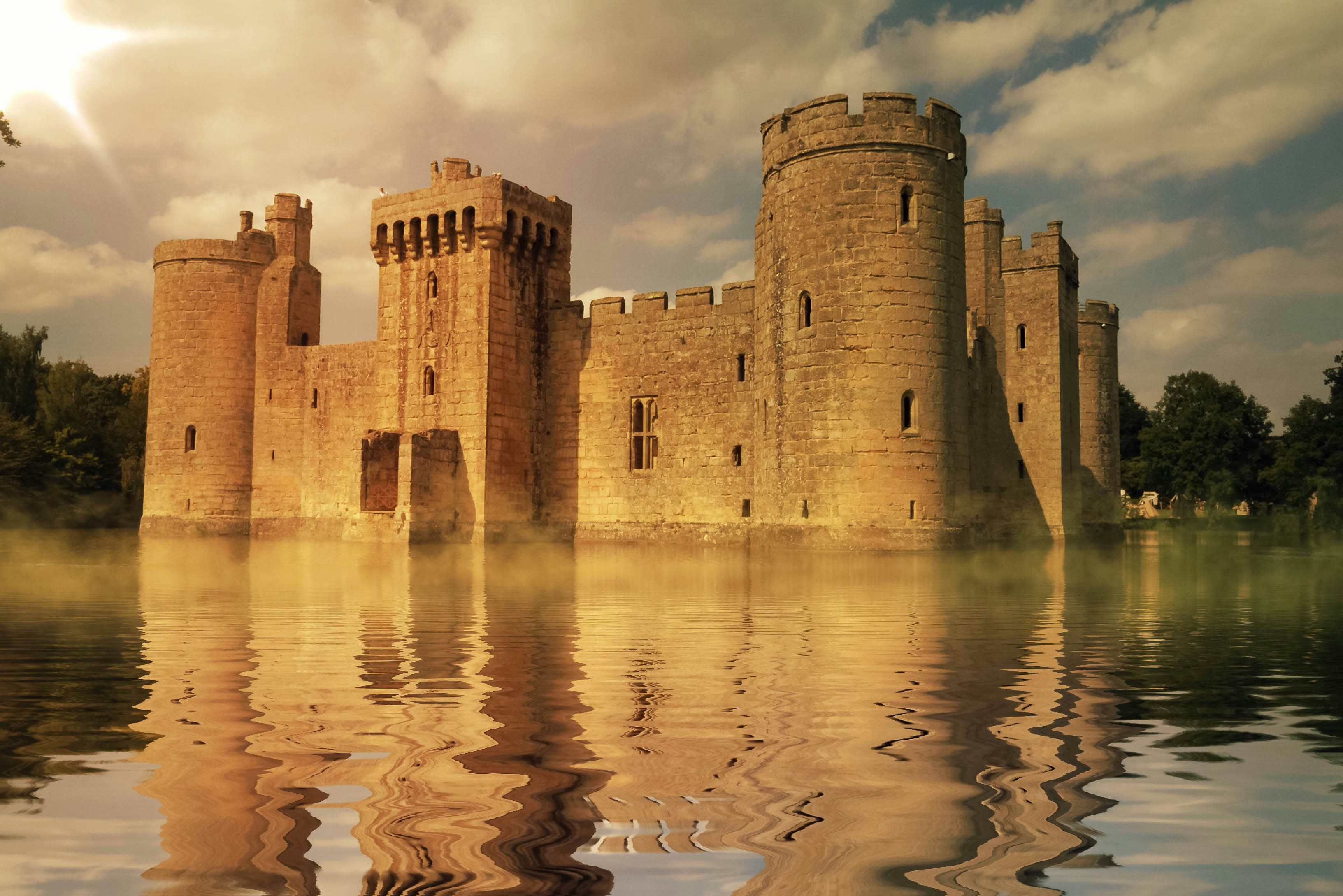 Well-preserved ruins on a castle sitting in an extensive moat in bright sunlight