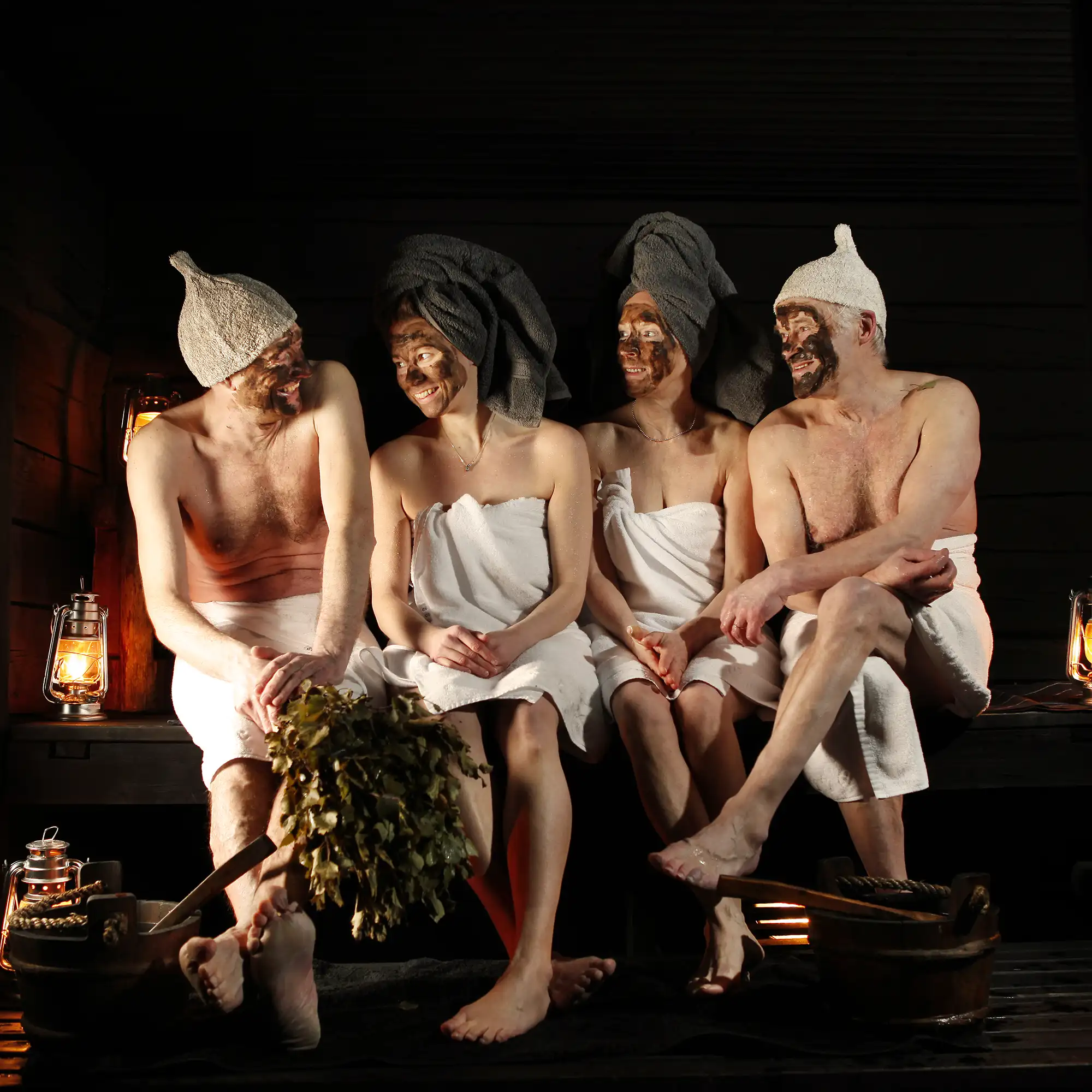 Wellness rustikal: vier Personen mit Schlamm-Maske sitzen in einer traditionellen Räucher Sauna