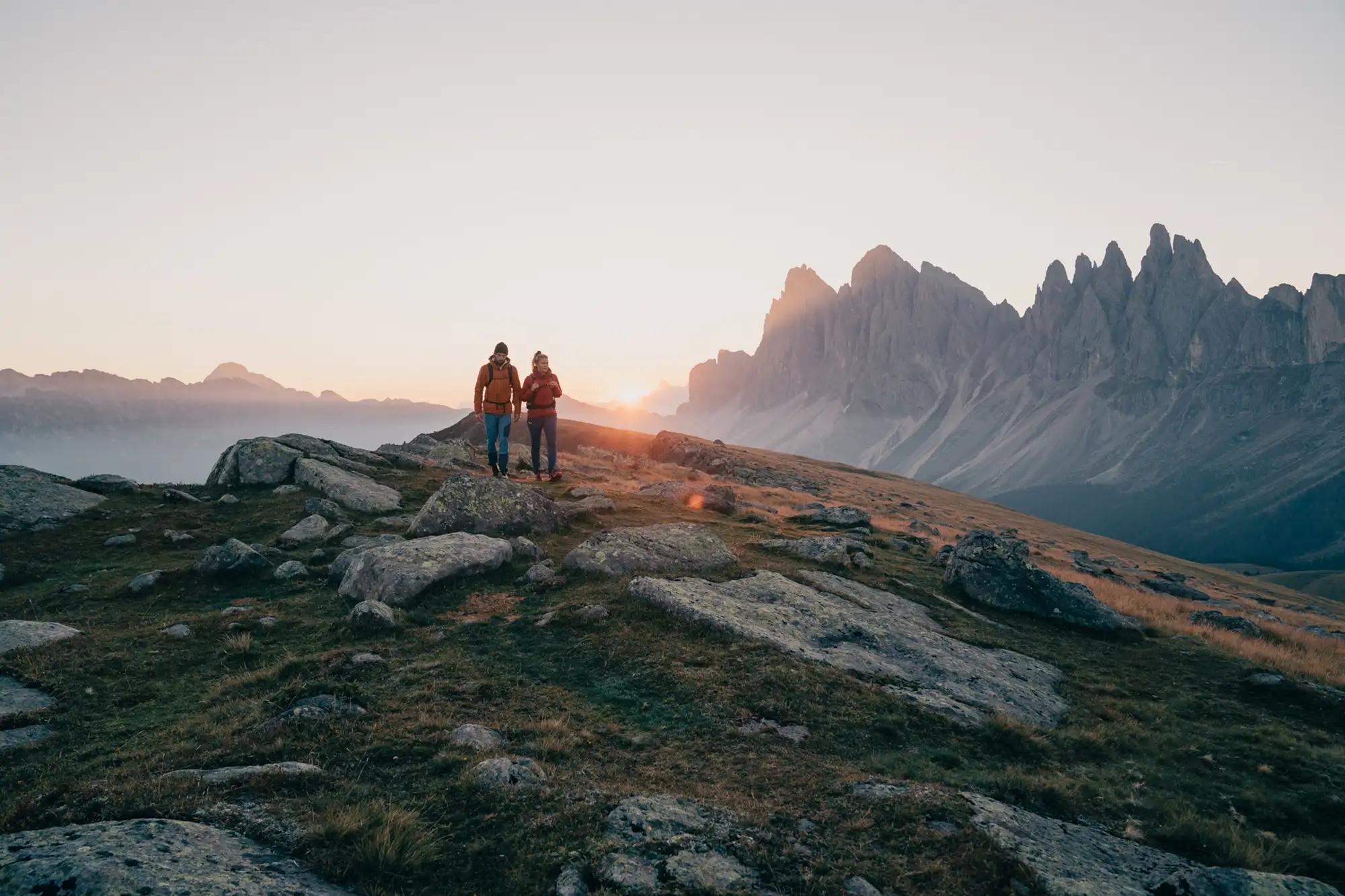 Zwei Wanderer in den Dolomiten, Italien. Im Hintergrund werden die Berge von der Sonne bestrahlt.