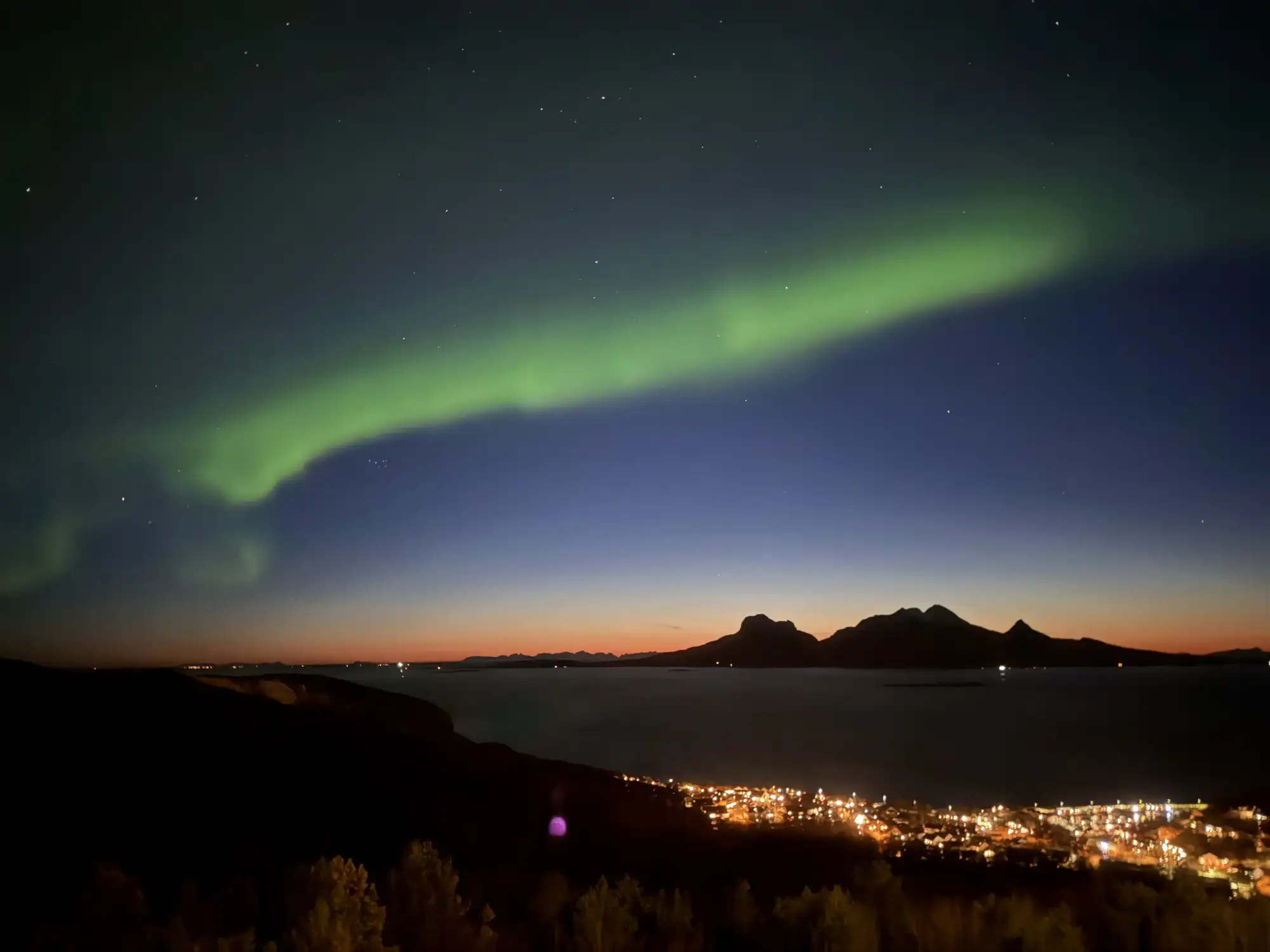 Grünes Nordlicht in der Nähe der Küstenstadt Bodö in Norwegen mit tollem Ausblick und Sternenhimmel.