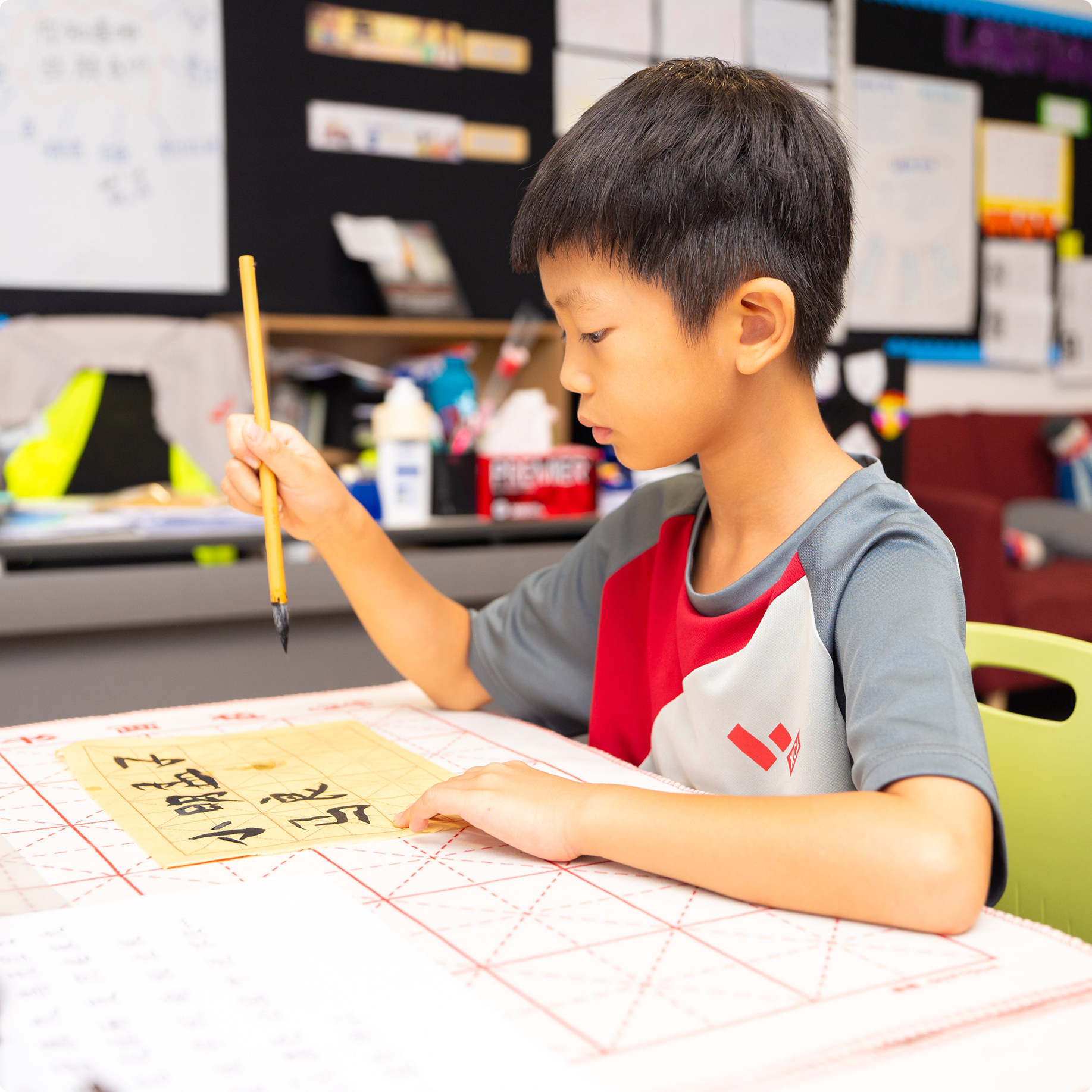 Student practising Chinese calligraphy with a brush in class