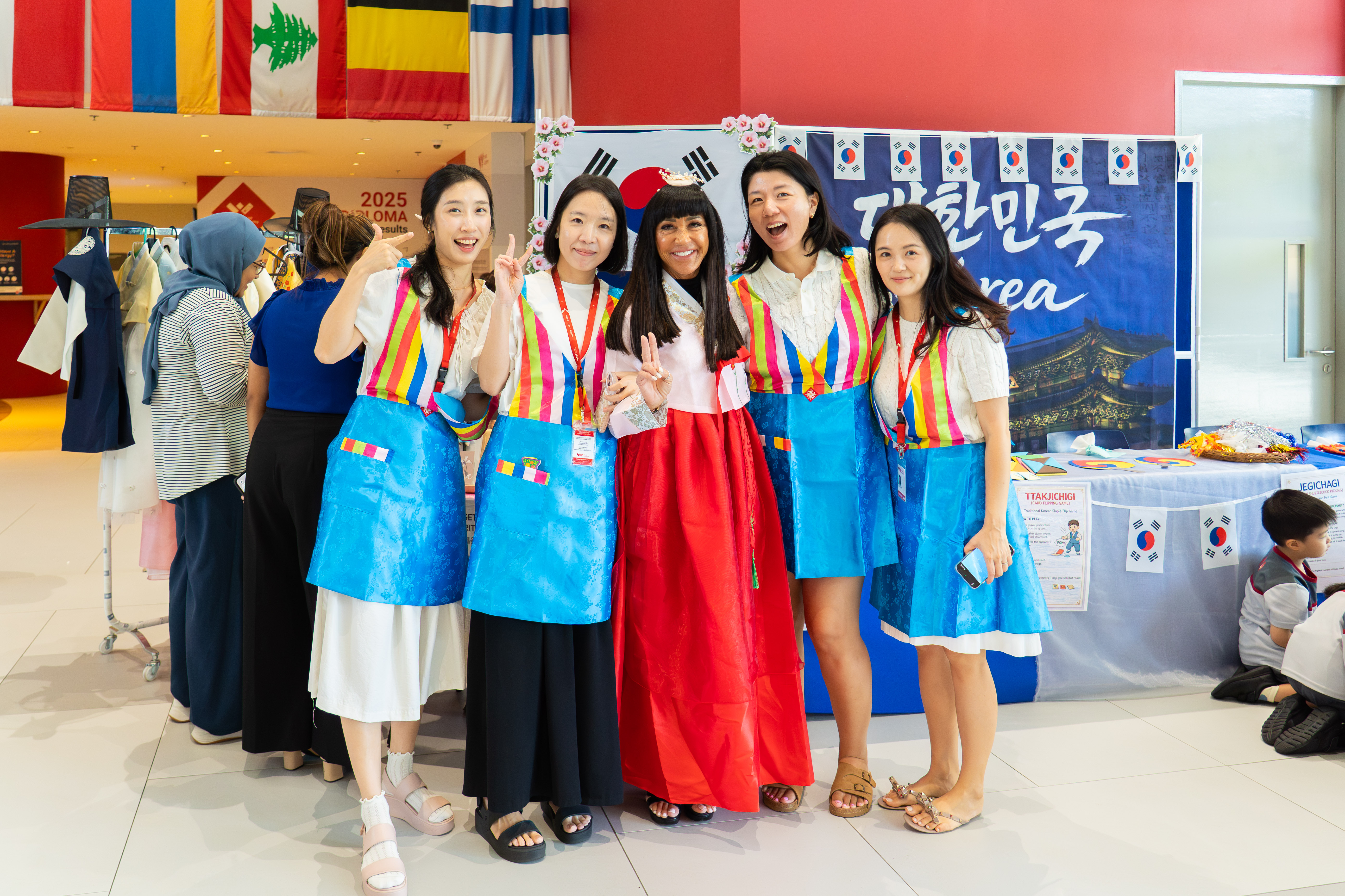 Five women in traditional Korean hanbok and aprons posing at a Korea booth during EYPY Language and Culture Week