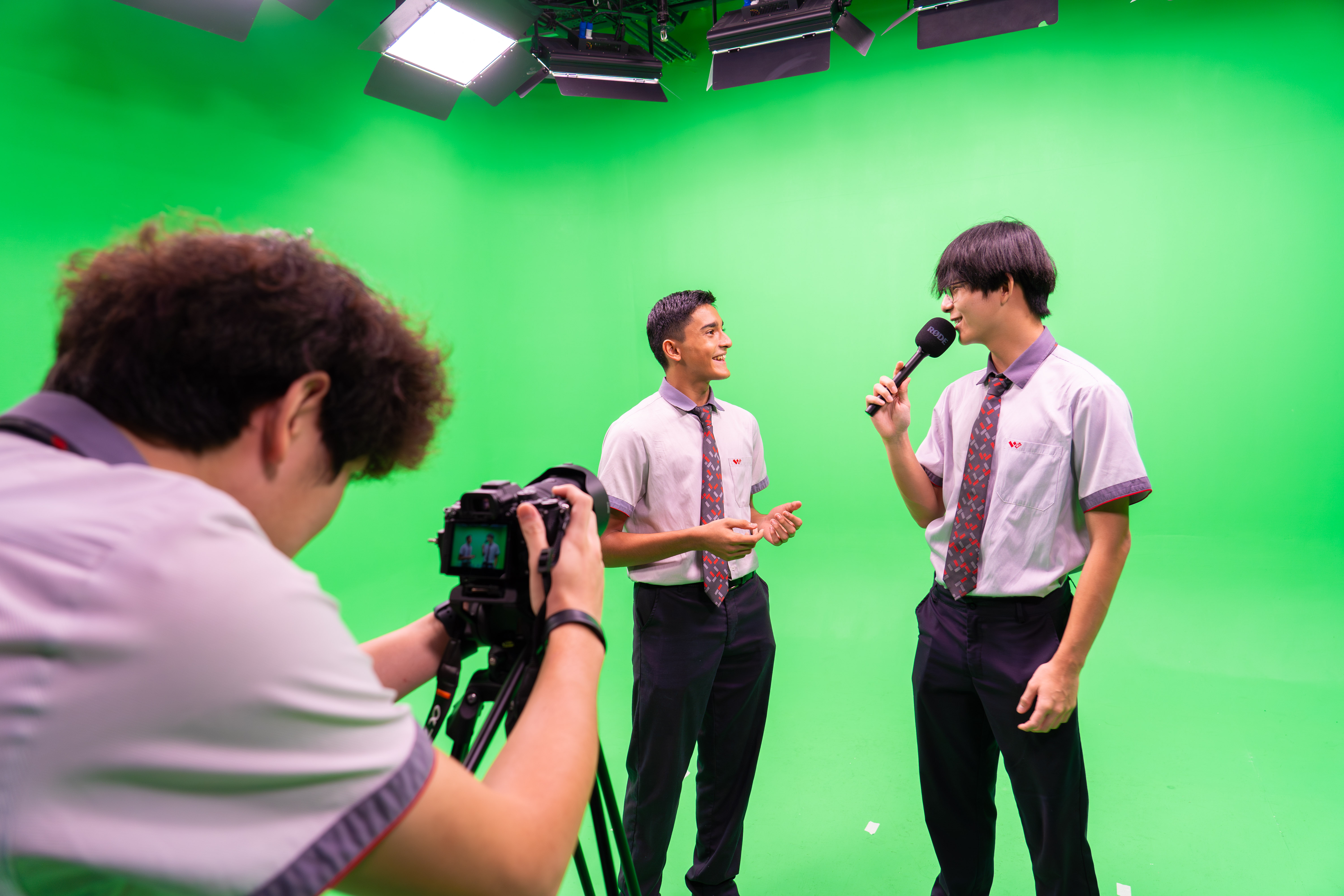 Students filming in a green screen studio, one interviewing another on camera
